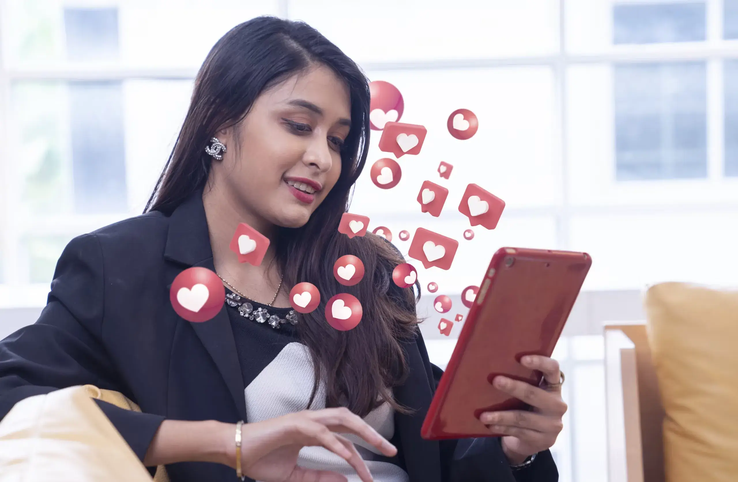 Blog 37 Woman engaging on social media using a tablet with floating heart icons.