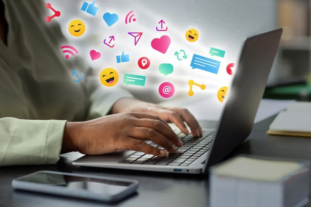 Blog 38 Person using laptop with social media and marketing icons floating around the screen.